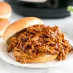 Slow Cooker Pulled BBQ Chicken sandwich piled high on a soft bun with rich barbecue sauce, ready to serve.
