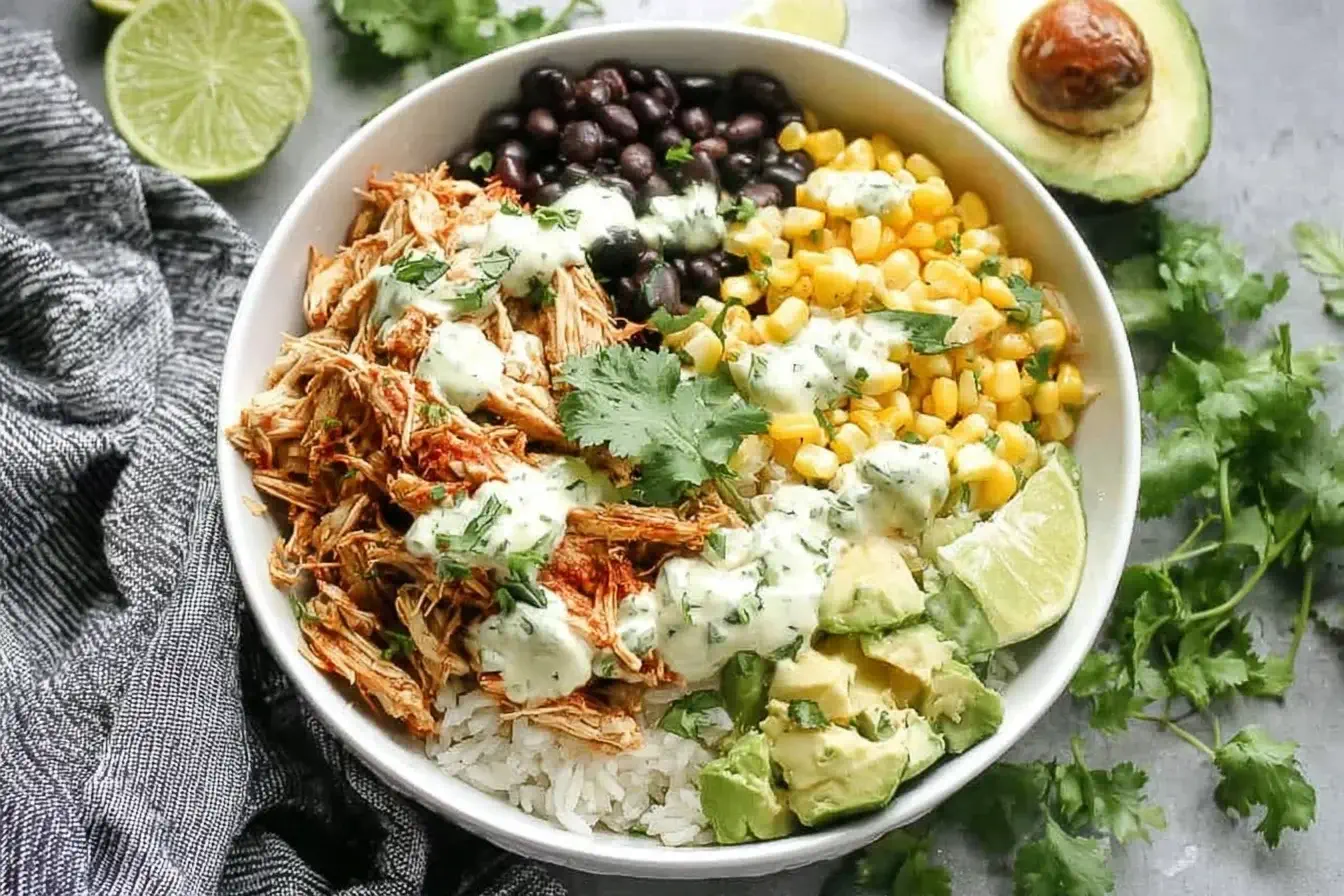 Slow Cooker Chicken Burrito Bowl with rice, beans, corn, avocado, and cilantro lime dressing