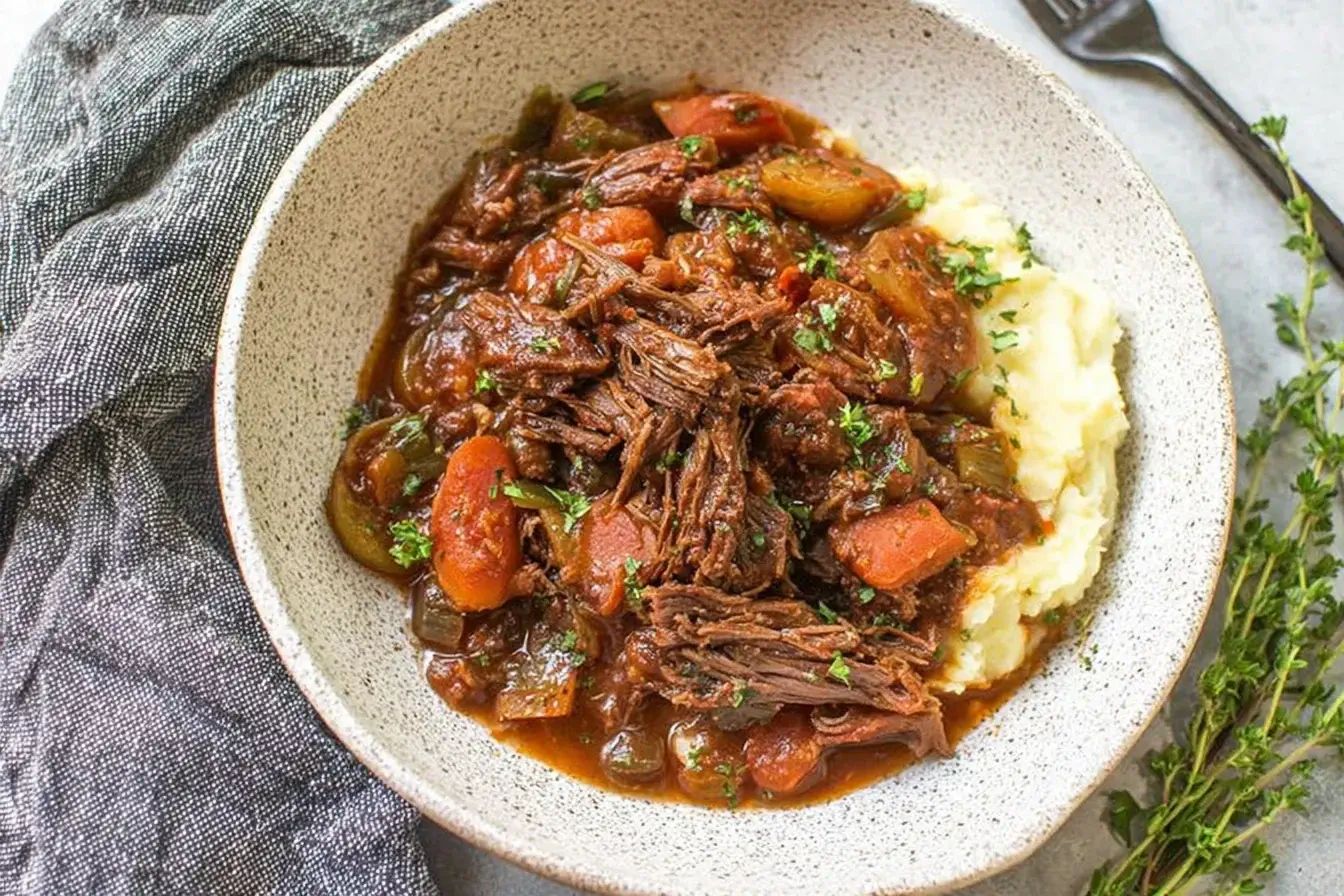 Slow Cooker Beef Ragu served over creamy mashed potatoes in a rustic bowl