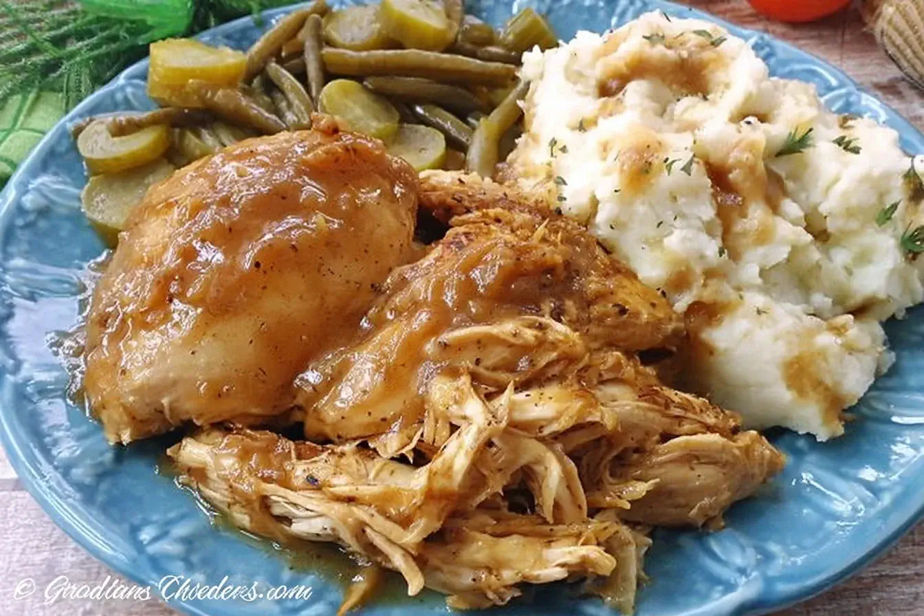 Crock Pot Mississippi Chicken served with mashed potatoes, gravy, and green beans on a blue plate.