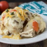 Crock Pot Pepper Jack Chicken topped with melted cheese, mushrooms, and carrots on a white plate.