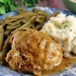 Crock Pot Mississippi Chicken with gravy, mashed potatoes, and green beans on a blue plate.
