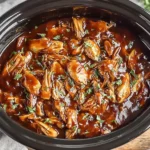 Crock Pot Bourbon Chicken in a rich, savory bourbon glaze topped with herbs.