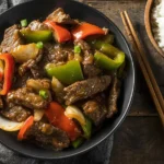 Slow Cooker Pepper Steak served with bell peppers and onions in a savory sauce, paired with white rice.