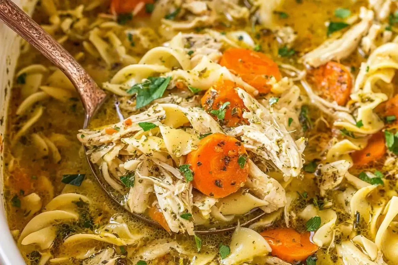 Slow cooker chicken noodle soup with shredded chicken, egg noodles, carrots, and herbs in a flavorful broth.