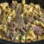 Crock Pot Beef and Noodles with shredded beef and egg noodles cooked in rich gravy inside a slow cooker.
