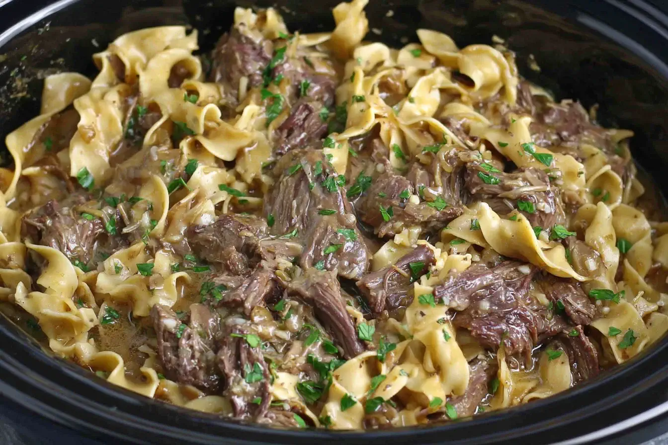 Crock Pot Beef and Noodles with shredded beef and egg noodles cooked in rich gravy inside a slow cooker.