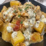 Slow Cooker Parmesan Garlic Chicken and Potatoes served with creamy sauce and herbs on a black plate