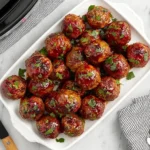 Sweet Chili Meatballs Crockpot served on a white platter, coated in glossy chili sauce and garnished with fresh parsley.