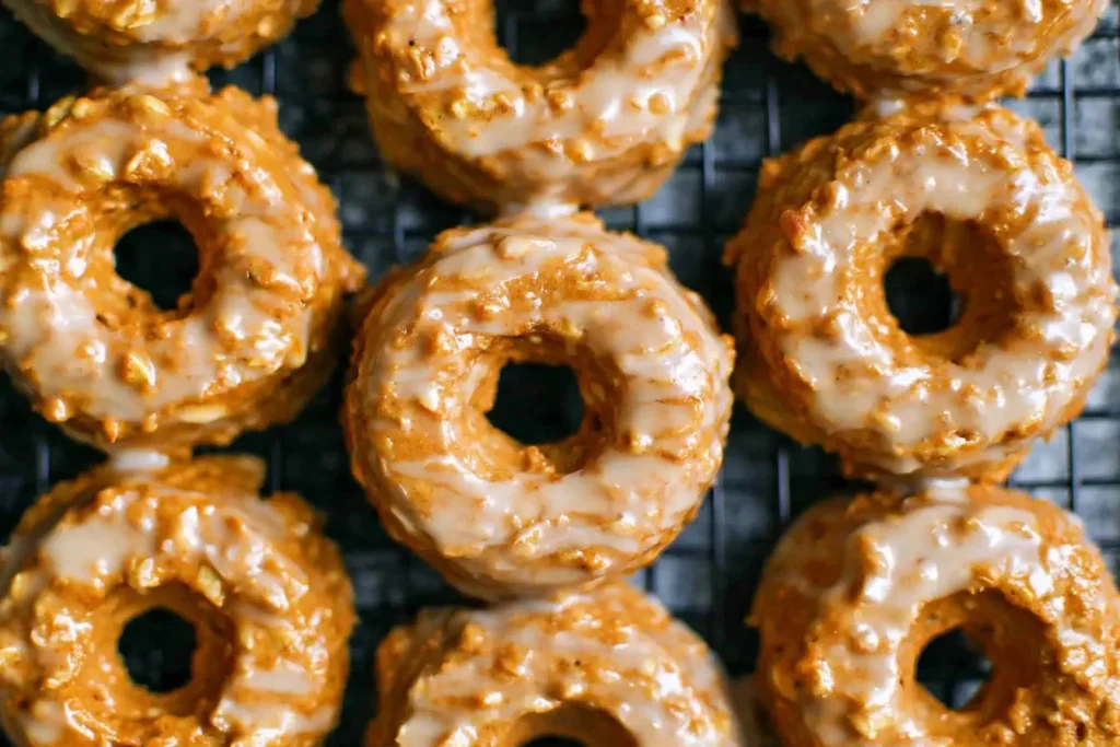 Close-up of freshly baked pumpkin donuts with maple glaze cooling on a wire rack.