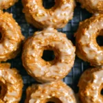 Close-up of freshly baked pumpkin donuts with maple glaze cooling on a wire rack.