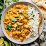 Crockpot Butter Chicken served with fluffy rice, naan, and fresh cilantro
