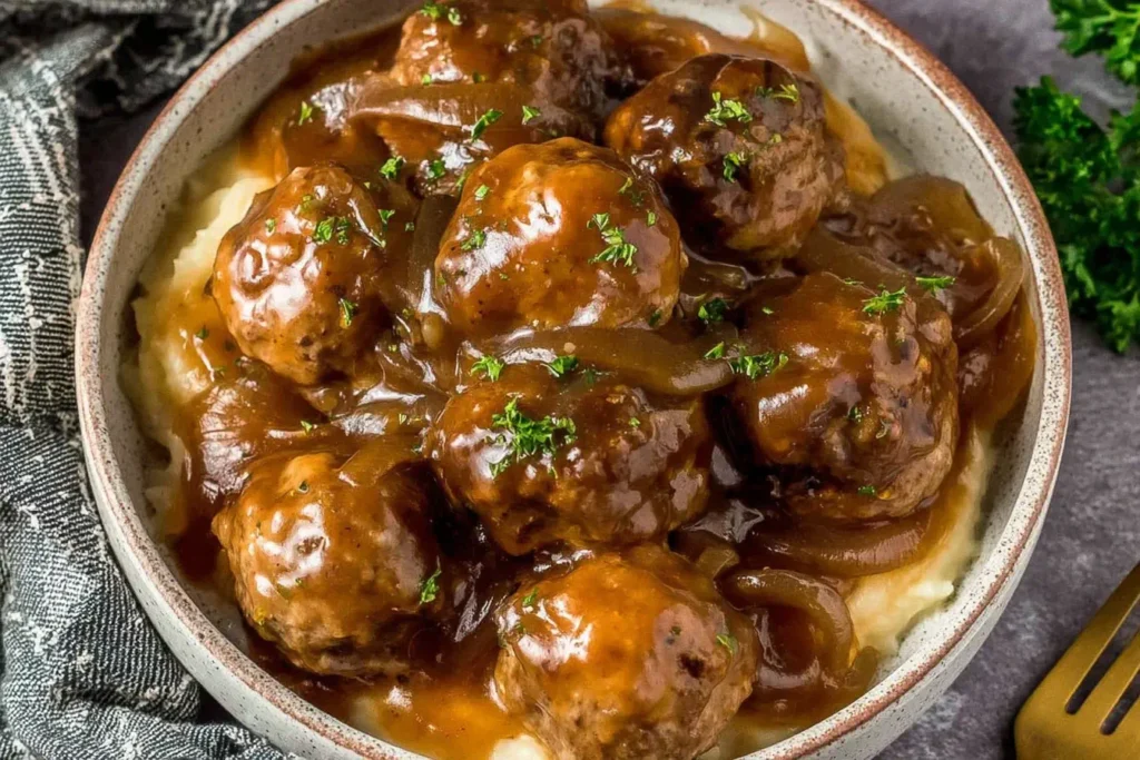 Crock Pot French Onion Meatballs served over creamy mashed potatoes with rich onion gravy and fresh parsley.