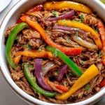 Crockpot Fajitas with colorful bell peppers and shredded chicken in a white bowl