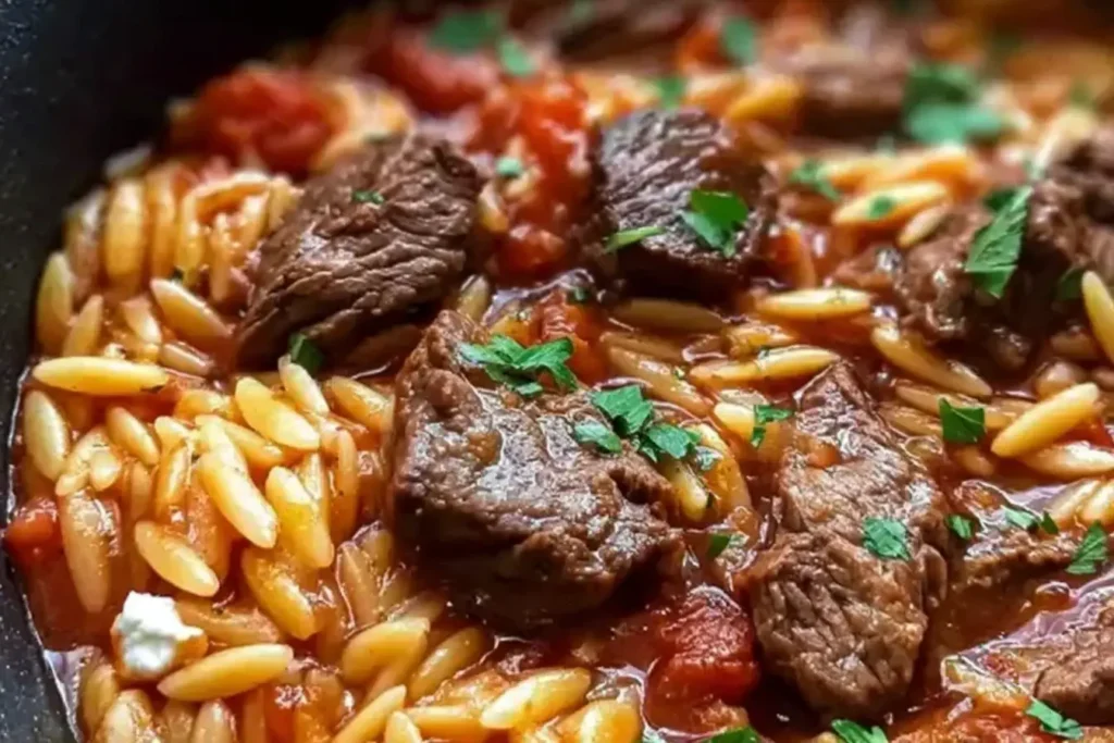Close-up of Beef Giouvetsi with tender beef chunks, orzo pasta, and rich tomato sauce garnished with fresh parsley.
