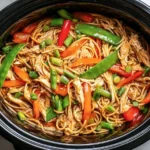Colorful Crockpot Chicken Lo Mein with noodles, shredded chicken, bell peppers, and snow peas in a slow cooker.