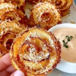 Close-up of crispy Parmesan Onion Rings served with creamy dipping sauce and fresh herbs.