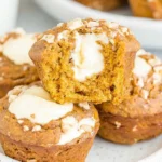 Moist Starbucks Pumpkin Cream Cheese Muffins with creamy centers and crunchy topping stacked on a white plate.