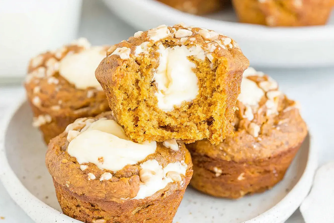 Moist Starbucks Pumpkin Cream Cheese Muffins with creamy centers and crunchy topping stacked on a white plate.