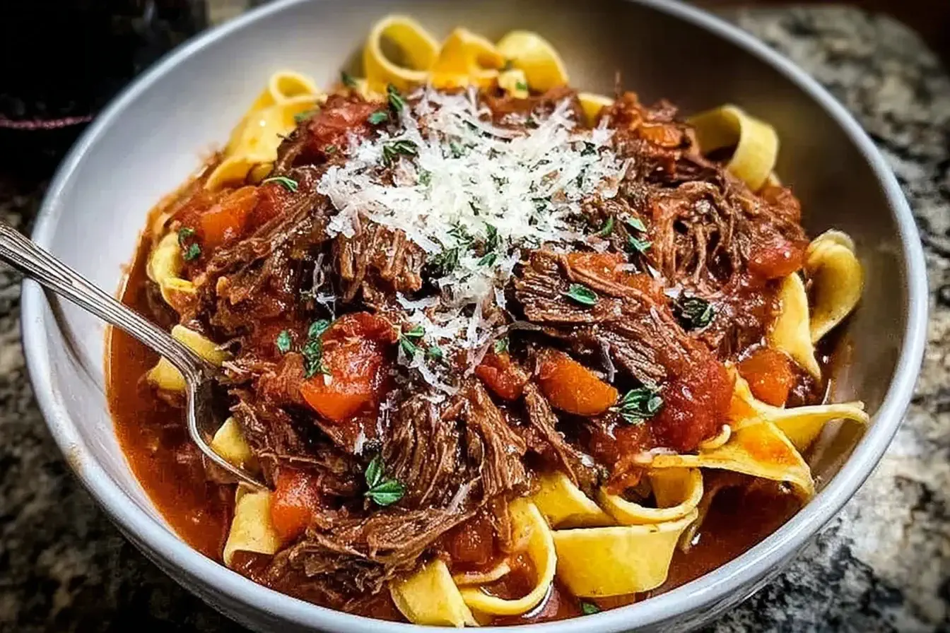 Hearty bowl of Sunday Slow Cooker Beef Ragu served over pappardelle pasta, topped with Parmesan and fresh herbs.