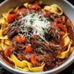 Close-up of Sunday Slow Cooker Beef Ragu served over ribbon pasta, topped with fresh herbs and shredded Parmesan.