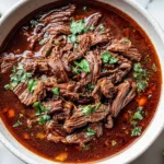 Bowl of savory Crockpot Mexican Beef Birria topped with fresh cilantro and lime slices.