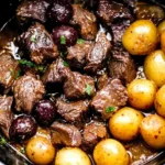 Crockpot Garlic Butter Beef Bites with Potatoes simmering in slow cooker with tender beef, baby potatoes, and rich garlic butter sauce.