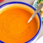 Bowl of creamy fresh tomato soup with croutons on the side