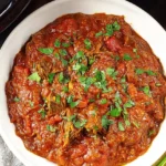 Bowl of Slow Cooker Beef Curry topped with fresh parsley, served as a hearty and flavorful dinner.