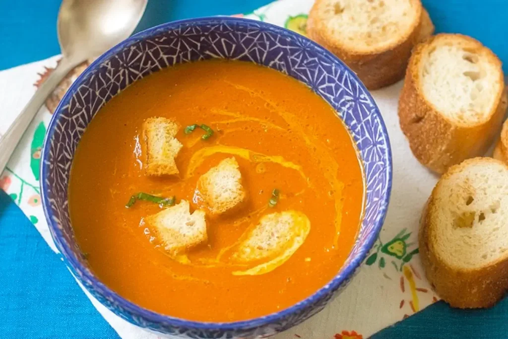 Bowl of fresh tomato soup with croutons and baguette slices