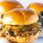 Slow Cooker Cowboy Sandwiches with shredded beef, cheese, and jalapeños on a toasted bun.