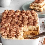 Creamy Pumpkin Tiramisu dessert layered with mascarpone, pumpkin spice, and cocoa powder in a white baking dish.