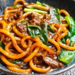 Beef Black Pepper Udon with tender beef, chewy noodles, and glossy pepper sauce in a bowl.