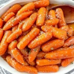 Tender Slow Cooker Maple and Brown Sugar Glazed Carrot topped with fresh herbs in serving dish