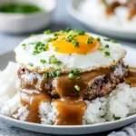 Hawaiian Loco Moco with rice, juicy beef patty, savory brown gravy, and a fried egg topped with fresh chives.