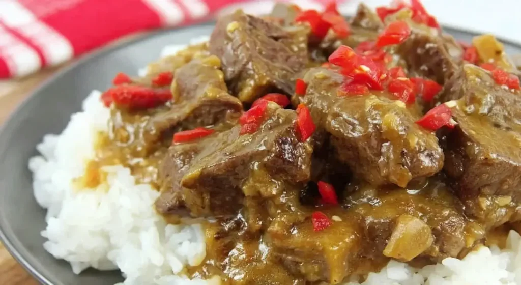 Slow Cooker Satay Beef served over white rice with fresh red bell pepper slices.