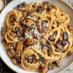 Creamy Caramelized Leek and Mushroom Gruyere Pasta served in a white bowl, topped with grated cheese and golden mushrooms.
