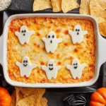 Spooky Halloween Buffalo Chicken Dip topped with ghost-shaped cheese and served with tortilla chips.