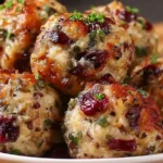 Cranberry Turkey Stuffing Balls baked golden brown with fresh herbs and cranberries on a white plate