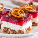 Multiple slices of Cranberry Pretzel Salad arranged on a white plate with mini pretzels on top.