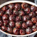 Spicy Cranberry BBQ Meatballs simmered in rich barbecue and cranberry sauce, garnished with herbs.