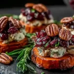 Sweet Potato Rounds with Brie Cranberry and Pecans topped with toasted pecans and cranberries on a slate serving board