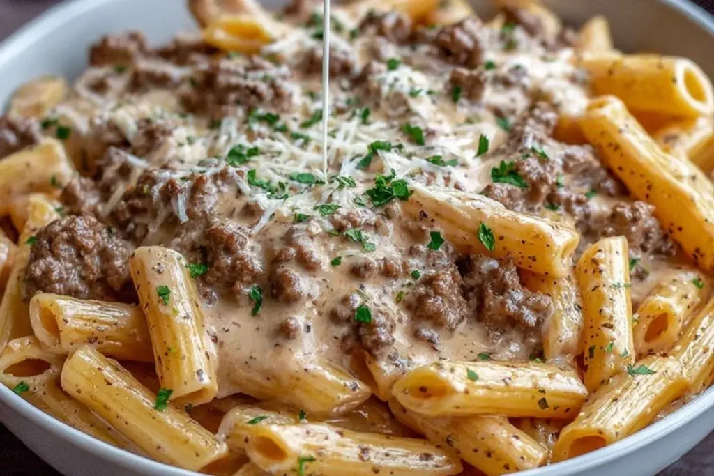 Slow Cooker Creamy Garlic Beef Pasta topped with rich creamy sauce, tender beef, and parsley in a white bowl