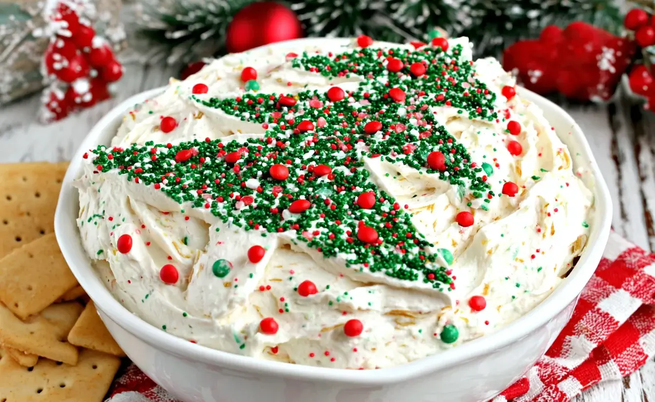 Festive Little Debbie Christmas Tree Cake Dip topped with green and red sprinkles shaped like Christmas trees in a white serving bowl.