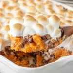 Spoonful of creamy Sweet Potato Casserole with Marshmallows topped with toasted marshmallows and crunchy pecans.