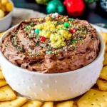 Chocolate Christmas Crack Dip in a white bowl topped with festive sprinkles and served with saltine crackers