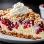 A slice of Cranberry Cream Cheese Crumb Pie with creamy filling, vibrant cranberry layer, and golden crumb topping served on a white plate.