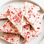 Salted Peppermint Bark stacked on a plate with crushed peppermint pieces