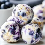 Close-up of Blueberry Cheesecake Protein Bites stacked together, showing creamy texture, oats, and fresh blueberries.