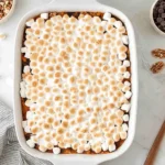 Golden-brown Sweet Potato Casserole with Marshmallows topped with toasted mini marshmallows in a white baking dish.